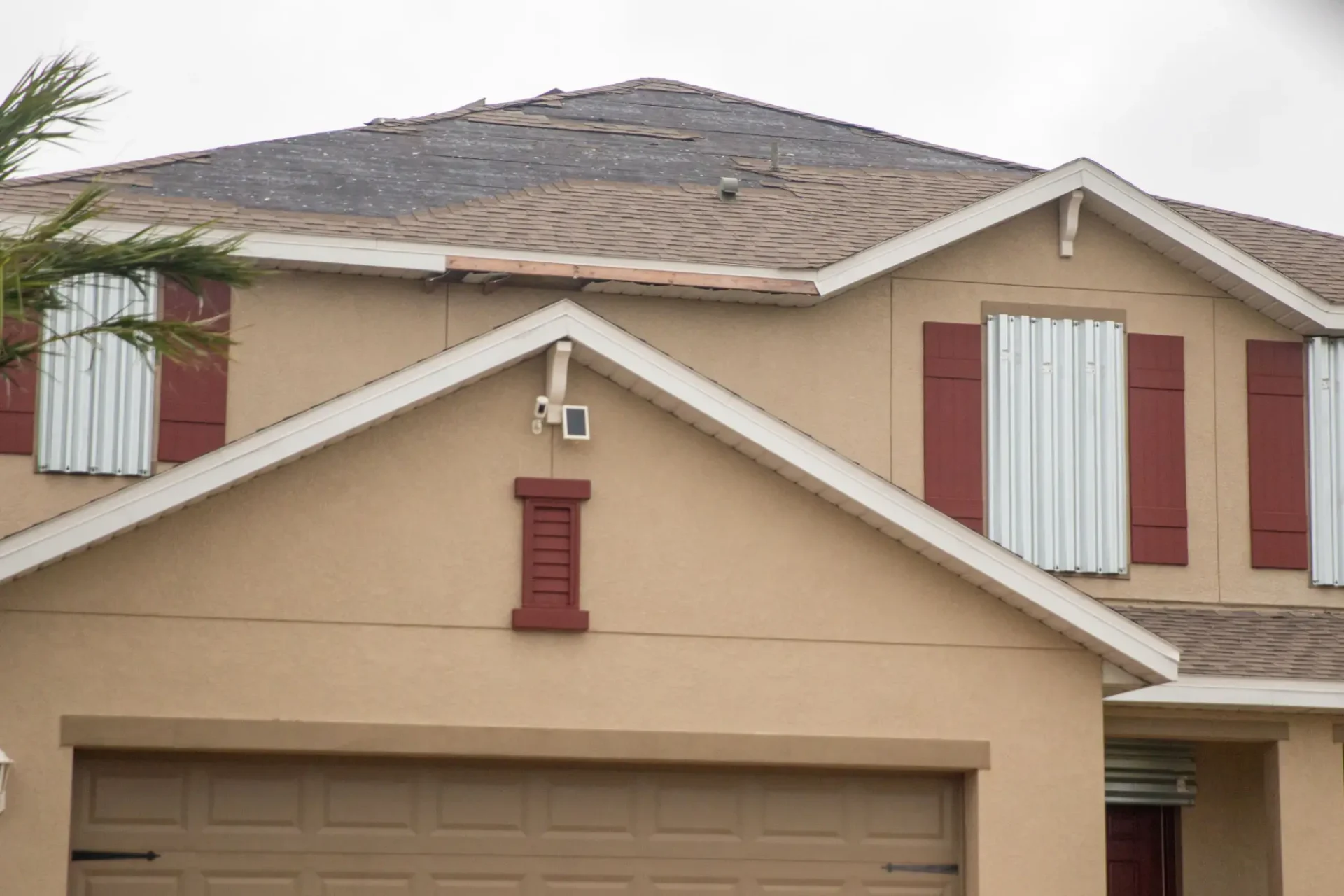 House with storm shutters and damaged roof