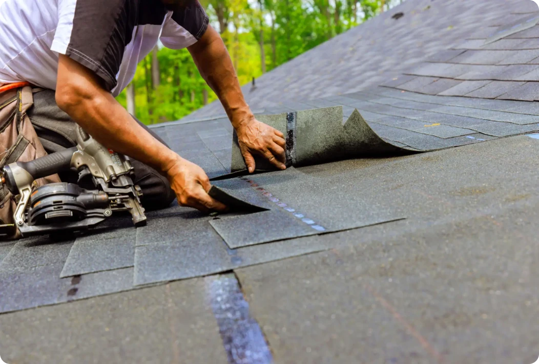 Worker laying roofing shingles